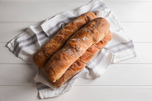 istock Fresh crispy ciabattas on white wooden table, top view 1478196361
