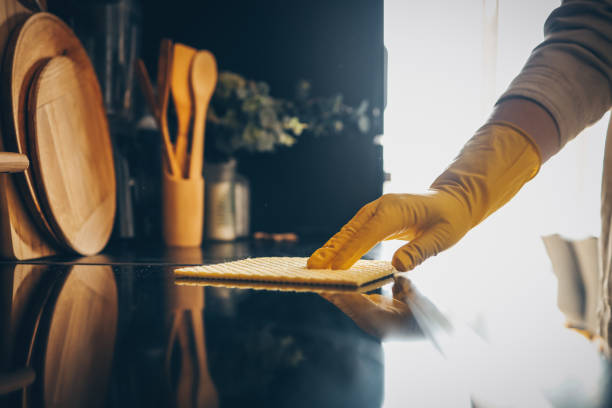 istock Closeup on woman's hands in yellow protective rubber gloves cleaning kitchen cabinets with sponge. 1478197172