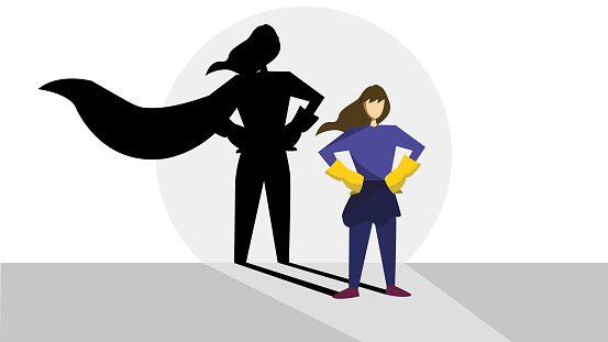 There is a woman with superhero shadow. She is wearing white gloves. Behind the woman there is a shadow which has cloak. The shadow seems like she is a hero. The background is pale.