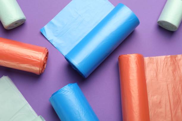 istock Rolls of different color garbage bags on violet background, flat lay 1478198381