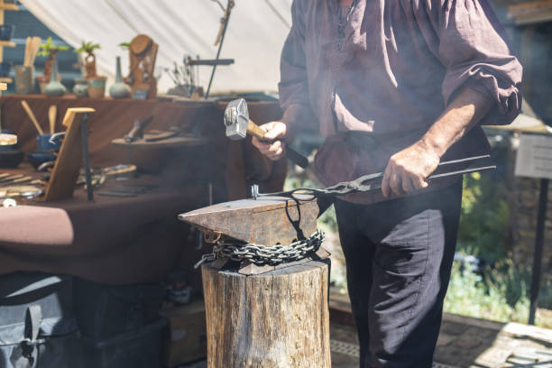 Caucasian male blacksmith forges iron in an anvil.