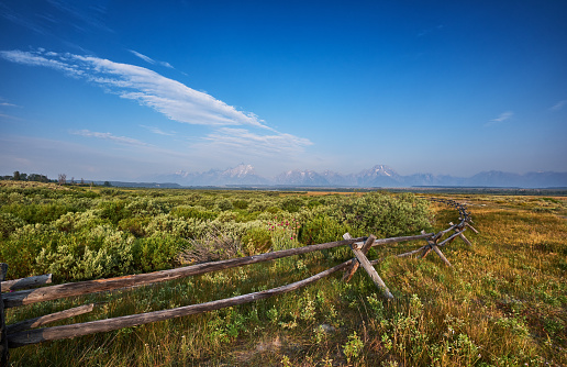 The Sawtooth Range sits in the distance in  a  fenced meadow, in the Sawtooth National Recreation Area of Stanley, Idaho. 