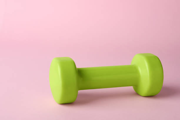 istock One green dumbbell on light pink background 1478200206