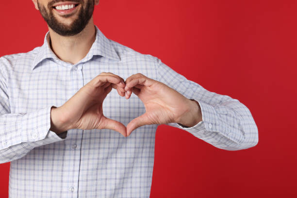 istock Man making heart with hands on red background, closeup 1478201790
