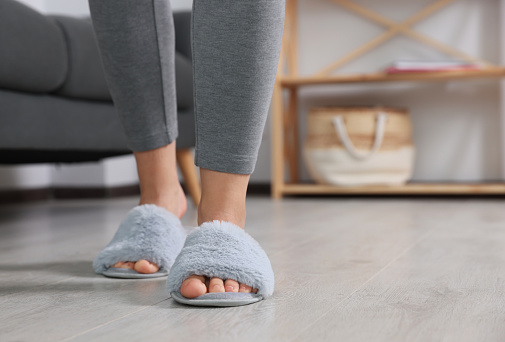 Woman wearing light blue soft slippers at home, closeup. Space for text