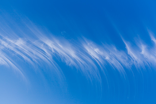 Unique wispy cirrus cloud patterns in a blue sky