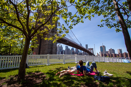 USA, April, New York: People are sitting nearby Brooklyn bridge during a sunny day in New York. Picnic in famous place  Emily Warren Roebling Plaza Brooklyn, New York.