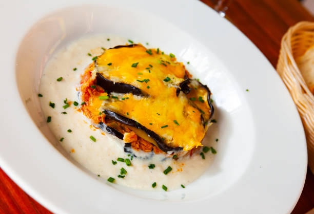 Gourmet Balkan Moussaka with aubergine and tuna in creamy sauce on white plate