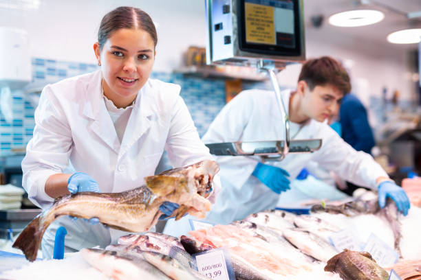 istock Positive saleswoman holding cod fish in fish store 1478206246