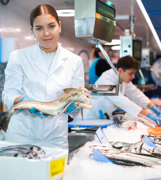 istock Positive saleswoman holding cod fish in fish store 1478206295