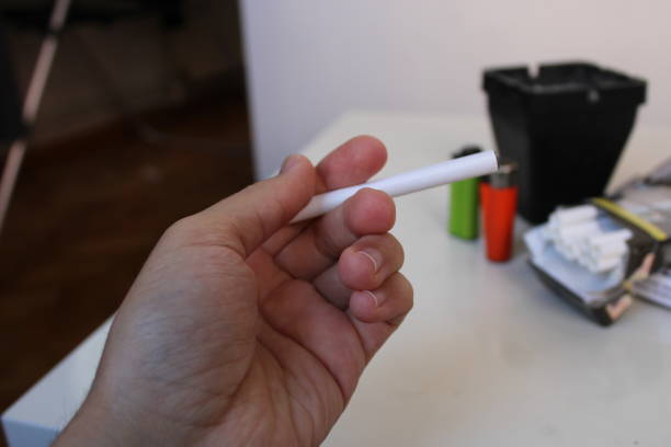 istock A hand holds a cigarette in a black box with a green label that says'smoke'on it. 1478207576