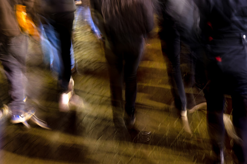 picture with camera made motion blur of a crowd of young people walking the rainy city at night