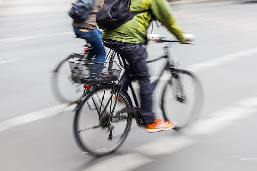 picture of two bicycle riders on a city street iwith camera made motion blur