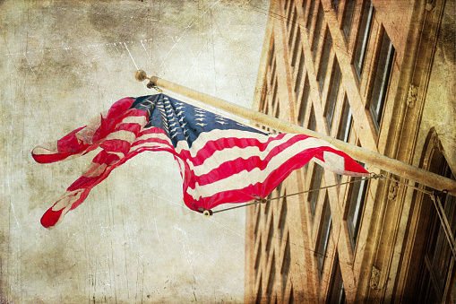 vintage textured picture of a waving US flag on a building wall in NYC