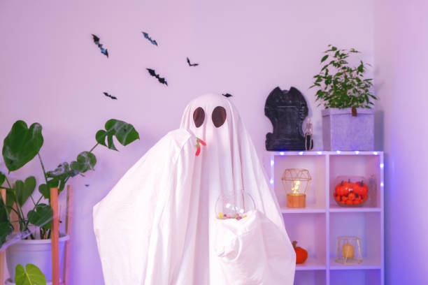 istock ghost eats Halloween sweets. A ghost eats worms, candy, sweets or muck, purse or life. Merry Halloween. 1478226159