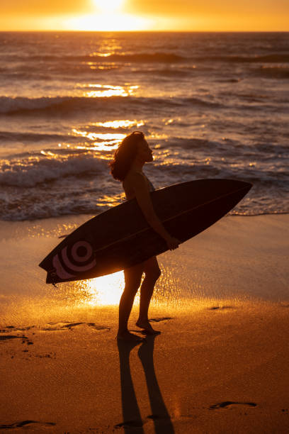 istock Anonymous lady with surfboard admiring nature on sandy seashore at sundown 1478227792