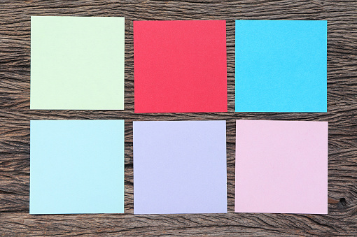 Different paper notes on wooden background. blank colorful sticky notes with space for text
