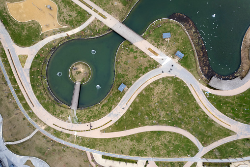 An aerial view of the walkways, trees, and pond in a park