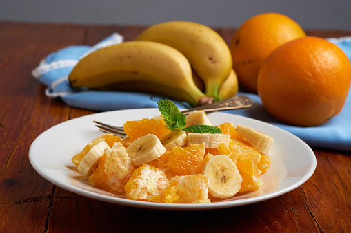 Refreshing and healthy mix of sliced bananas and oranges, vegan food.