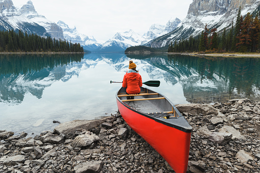Scenery of Spirit Island with female traveler on kayak by the Maligne Lake in the morning at Jasper national park
