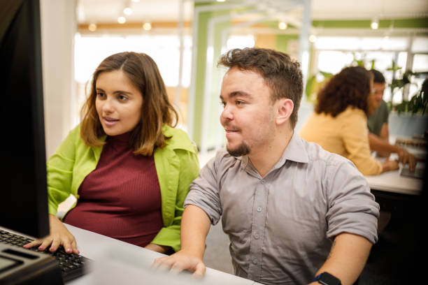 Man helping his pregnant coworker at work Man with dwarfism helping his pregnant coworker at work short stature stock pictures, royalty-free photos & images