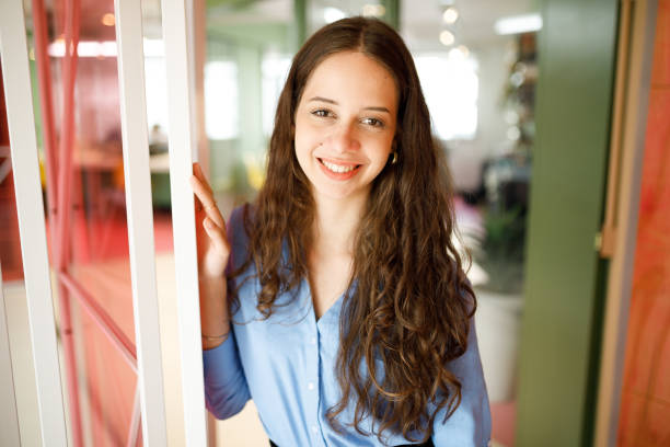 istock Long haired office lady smiling while holding the door 1478252286
