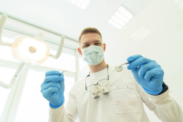 the dentist bends over the patient and is about to begin the examination