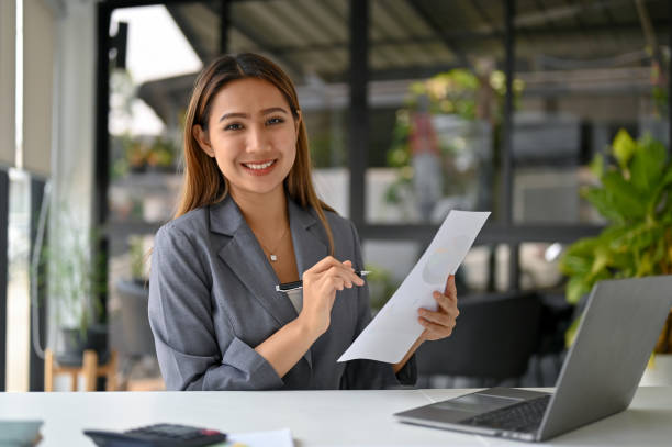 istock Charming Asian businesswoman analyzing financial data on reports, working at her desk. 1478262254