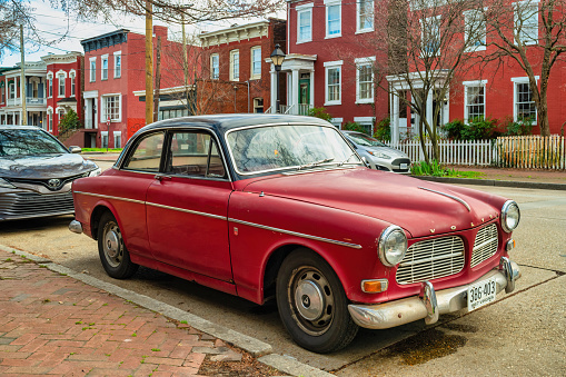 A vintage 1960s Volvo 122 (Volvo Amazon) is parked on the street in downtown Richmond, Virginia, USA on a cloudy day.