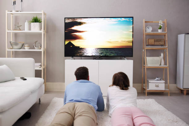 istock Young Couple Watching TV While Sitting On Sofa In Living Room 1478285178
