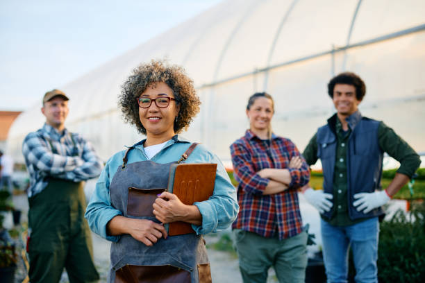 istock Happy greenhouse owner and group of her workers looking at camera. 1478288926