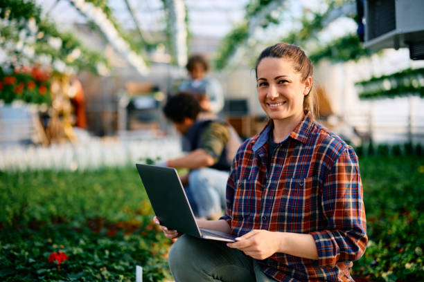 istock Happy plant nursery worker using laptop and looking at camera. 1478288974