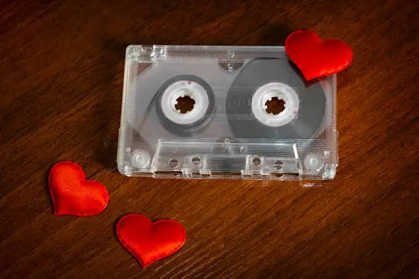 Audio Tape Cassette with a Red Hearts on the Wooden Table closeup