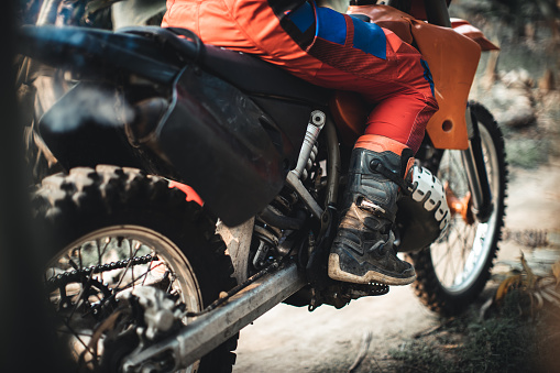 Kick-start an orange dirt bike on a dirt road, wearing full dirt bike gear and protection,  Banana Island, Hanoi