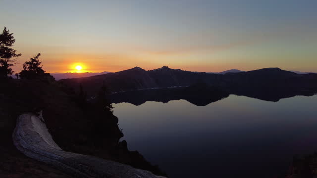 Panning Toward Sun Setting Over Mountain Ridge Behind Crater Lake