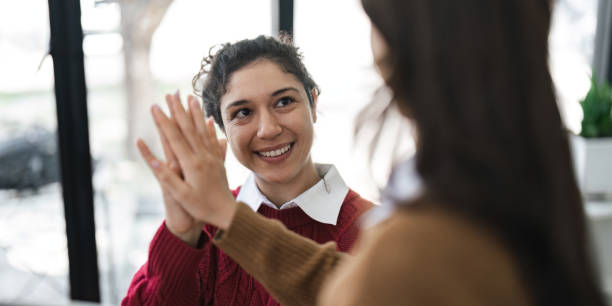 Successful business people giving each other a high five in a meeting. Two young business celebrating teamwork in an office. Successful business people giving each other a high five in a meeting. Two young business celebrating teamwork in an office.. chief of staff stock pictures, royalty-free photos & images