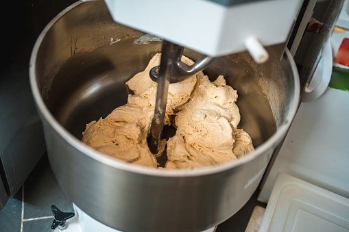 Close up dough mixing machine in action. Mixing dough in a stainless steel bowl.
