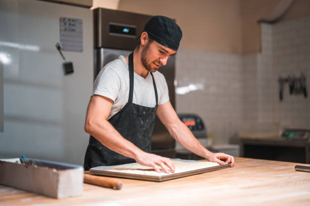 istock Caucasian Artisan Baker Shaping Dough On A Baking Tray 1478300510