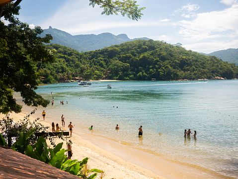 View of a golden sand beach and emerald water on a tropical island.