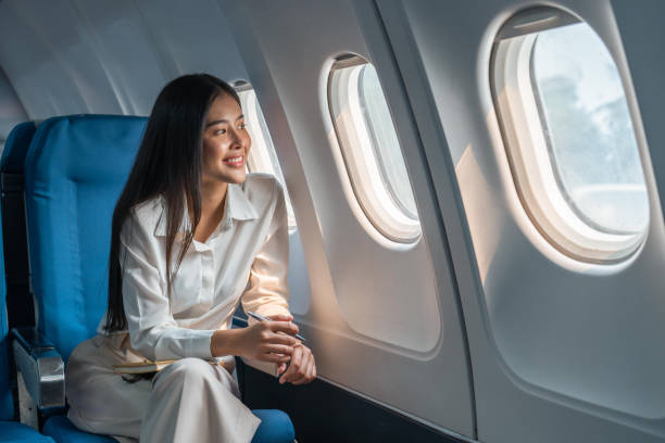 asiatische frau, die in einem flugzeug sitzt und aus dem fenster schaut, geht auf eine reise urlaub reisekonzept - fensterplatz fahrzeugsitz stock-fotos und bilder