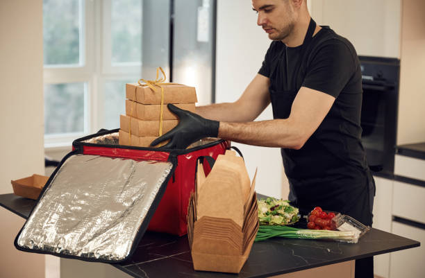 istock Focused on work. Man packs paper eco boxes into a bag for food delivery 1478304461