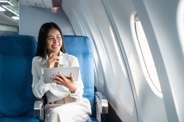 istock Young asian businesswoman in formal clothes working using tablet with smart pen while sitting in airplane cabin near window traveling to another place 1478304485