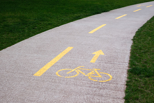 Highlighted in yellow paint is a bicycle path in a city park against a background of green grass.