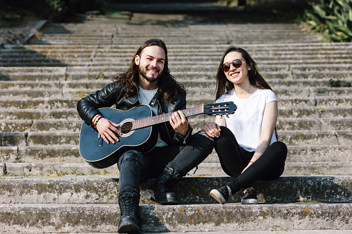 young latin couple man and woman in rock and roll style and playing guitar in the street in Mexico Latin America