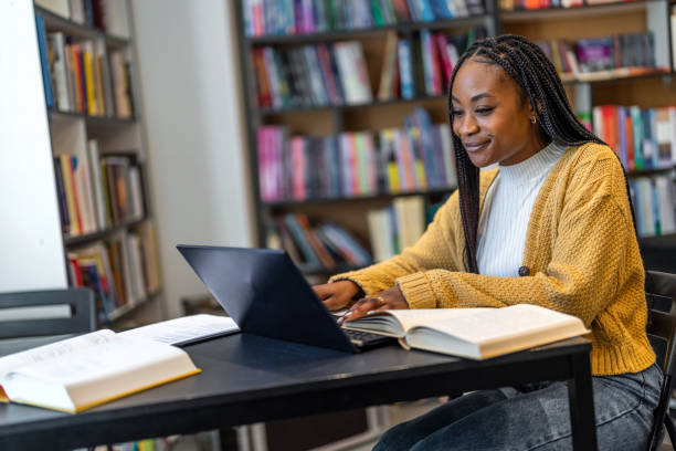 istock African american girl sitting in library using computer and writing notes 1478315996