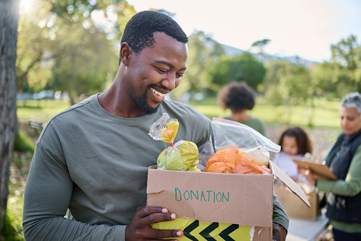 Food, donation and man in park with smile and grocery box, happy, healthy diet at refugee feeding project. Fresh fruit, charity donations and help to feed people, support from farm volunteer at ngo.