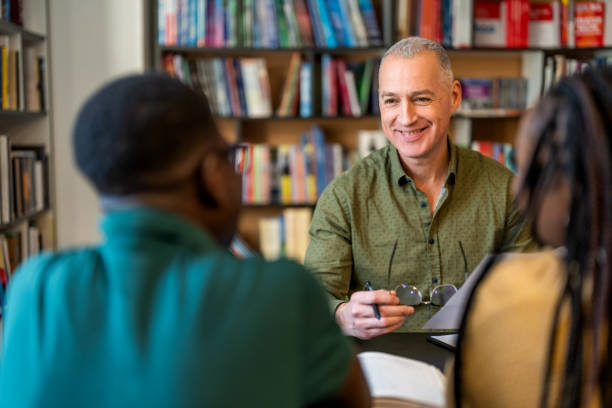 istock Male tutor discussion with college students in library. 1478316494