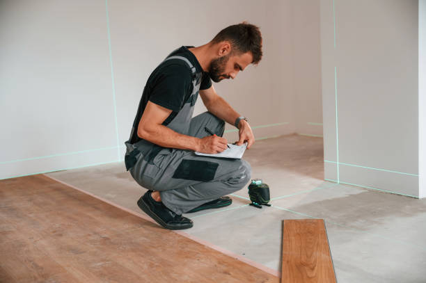 istock Sitting and making measurements by using laser leveler. Man is installing new laminate wooden floor 1478317972