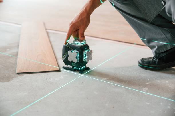 istock Using the device that shows straight lines by laser. Man is installing new laminated wooden floor 1478318108