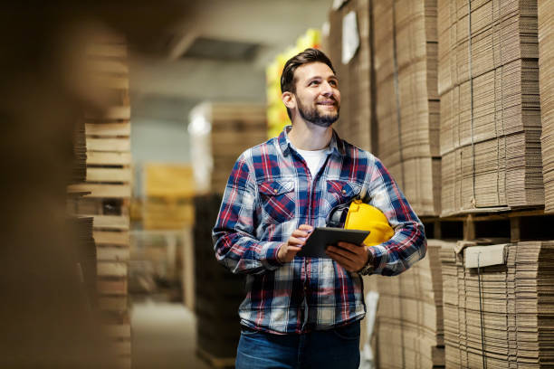 A paper and cardboard industry worker with tablet in hands inventorying in storage. stock photo